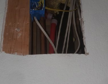 An opening in a wall with pipes and wiring.